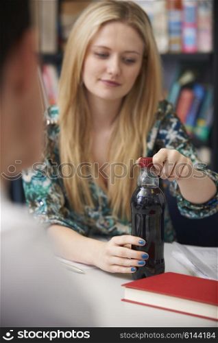 Teeange Female Student With Bottle Of Fizzy Drink In Class
