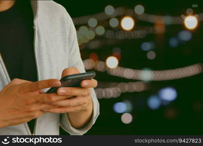 teen age hand using mobile phone against blur glow light abstract background