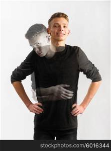 teen age issues. portrait of an insecure male caucasian teenager with two faces on gray background