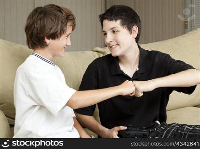 Teen and his younger brother giving each other an affectionate fist bump.