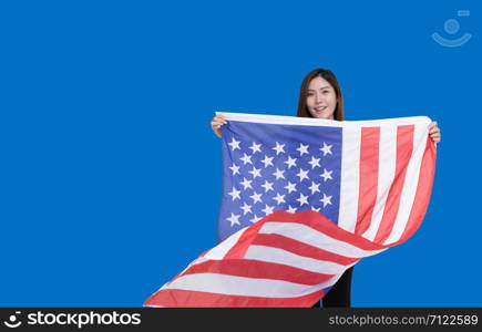 Teen Asian women holding the US flag with a smile of joy on a blue background. Asian-American women are proud of the American flag.