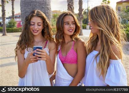 Teen best friends girls group playing with smartphone in palm trees beach