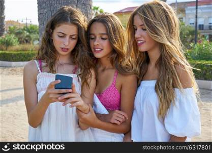 Teen best friends girls group playing with smartphone in palm trees beach
