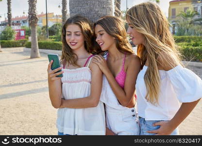 Teen best friends girls group playing with smartphone in palm trees beach