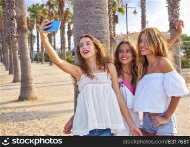 Teen best friends girls group shooting selfie photo smartphone in palm trees beach