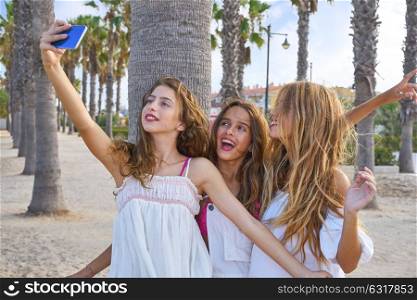 Teen best friends girls group shooting selfie photo smartphone in palm trees beach