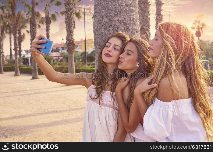 Teen best friends girls group shooting selfie photo smartphone in palm trees beach filtered image