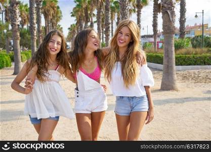Teen best friends girls group walking happy in a palm trees beach area