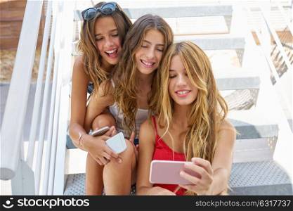 Teen best friends girls in a row with smartphone having fun on stairs