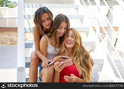 Teen best friends girls in a row with smartphone having fun on stairs