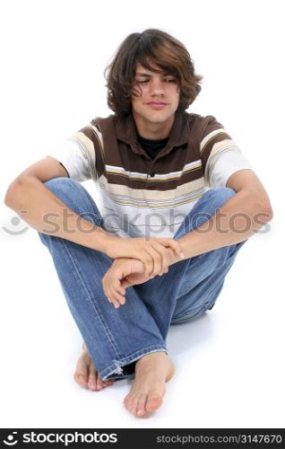 Teen boy in casual clothes sitting on white floor.