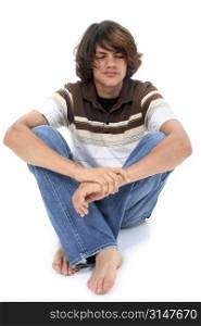 Teen boy in casual clothes sitting on white floor.