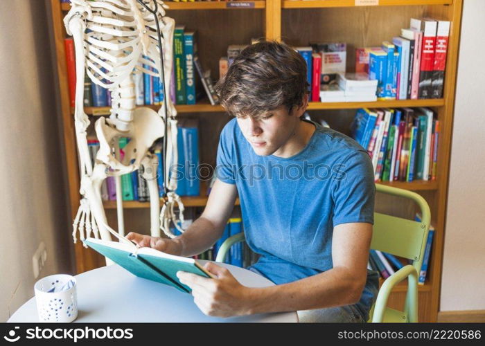 teen boy reading book library table
