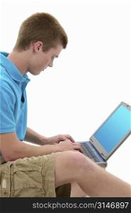 Teen boy working on laptop computer. Casual clothing, sitting on floor. Shot in studio over white.