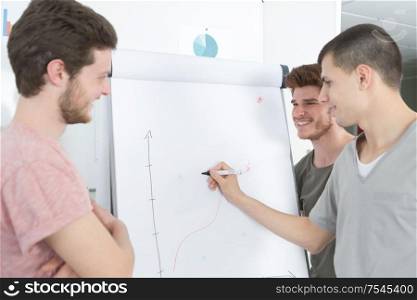 teen boys drawing diagrams on white board during class