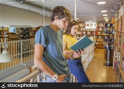 teen couple leaning railing reading