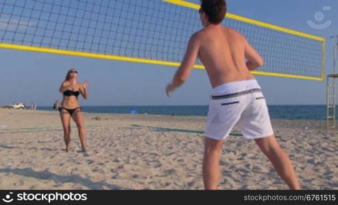 Teen couple playing volleyball on the beach