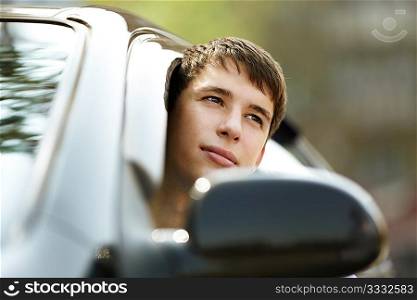 teen driver in good mood with black car, selective focus on eyes