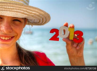 Teen girl at a beach holding wooden number &rsquo;2013&rsquo;
