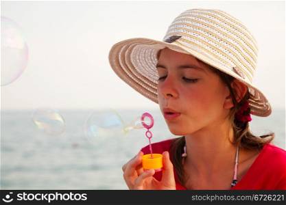 Teen girl blowing bubbles at sea shore