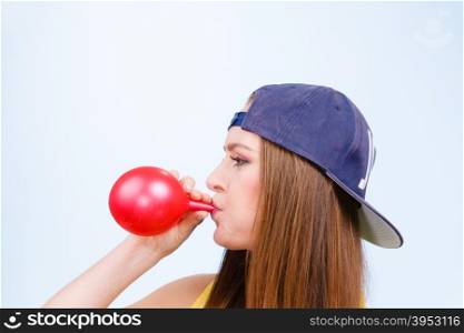 Teen girl blowing red balloon.. Teens and parties. Preparation for celebration. Trendy teenage girl blowing red balloon. Young beauty woman prepare accessories for party.