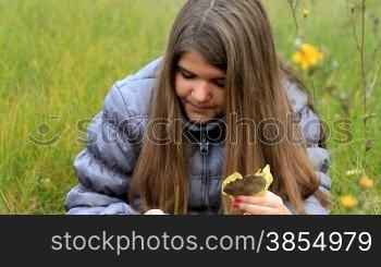 teen girl collects autumn leaves.