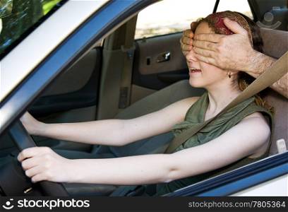 Teen girl gets the feel of the car while someone covers her eyes.