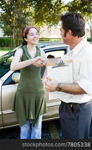 Teen girl getting a handshake from her driving instructor.