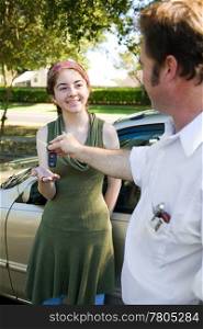 Teen girl getting car keys from her father or driving instructor.
