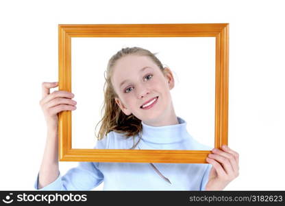 Teen girl holding wooden frame in front of face.