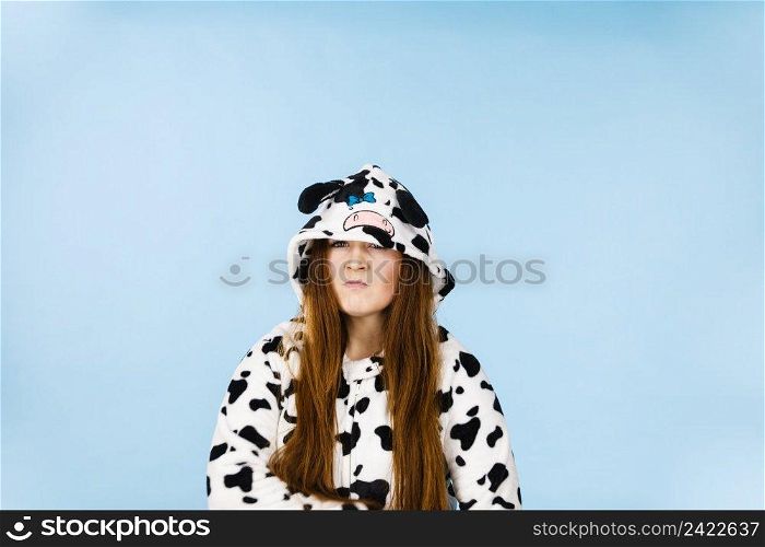 Teen girl in funny nightclothes, pajamas cartoon style showing angry offended face expression, studio shot on blue. Negative emotion concept.. Woman wearing pajamas cartoon angry expression