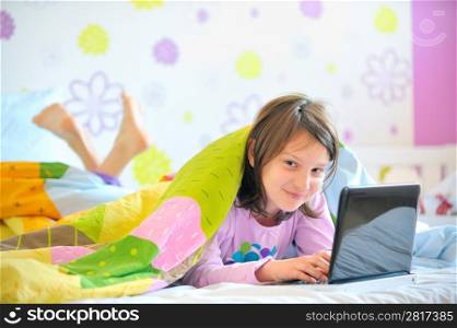 Teen girl in her bed looking on laptop
