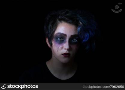 Teen girl in scary makeup on black background.