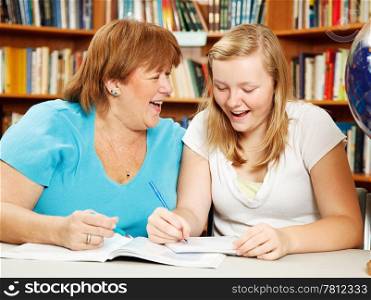 Teen girl in the library studying with her mother (or teacher.)