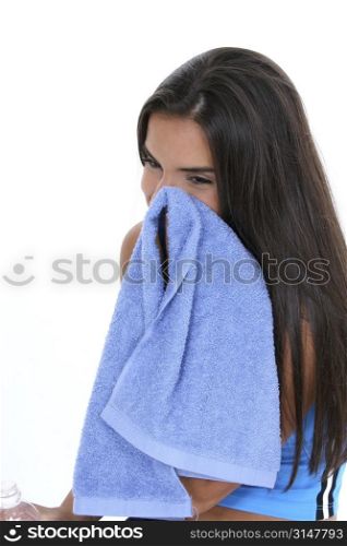 Teen girl in workout clothes with bottle of water, wiping face with towel.