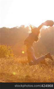 teen girl jumping on a meadow in sunset time