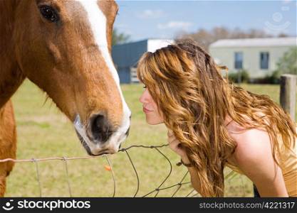 Teen girl kisses her horse on the nose.