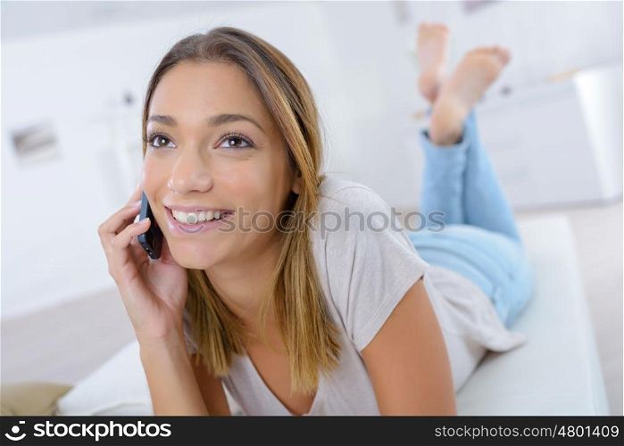teen girl laying on the sofa talking on the phone