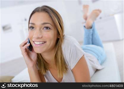 teen girl laying on the sofa talking on the phone