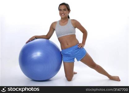 Teen girl leaning on exercise ball. Wearing workout clothes and barefoot.
