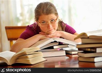 Teen girl learning at the desk, sitting on books