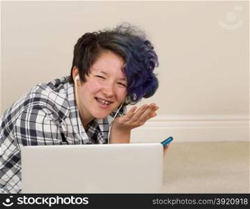 Teen girl, looking forward, with expression of leave me alone holding cell phone while on compute listening to music.