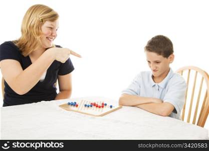 Teen girl makes fun of her little brother during a board game. White background.