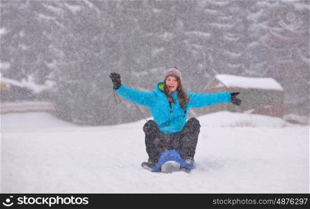 Teen girl on sledge in snowy winter forest