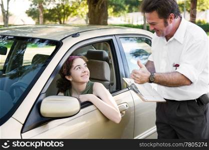 Teen girl passes her driving test and gets a thumbs up from her instructor.