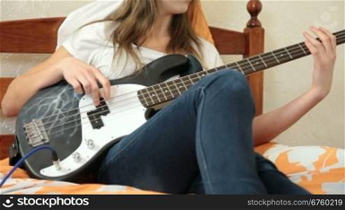 Teen Girl Playing Bass Guitar At Home