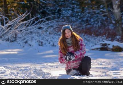 teen girl playing in snow throwing snowball at camera