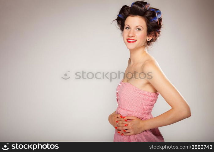 Teen girl preparing to party getting ready for going out. Young woman with hair curlers pin up makeup studio shot on gray. Hairstyle