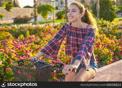 Teen girl riding bicycle in a city flowers park happy