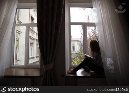 teen girl sitting on a windowsill with a book in the children's room